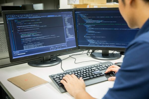 Programmer working on two computer screens