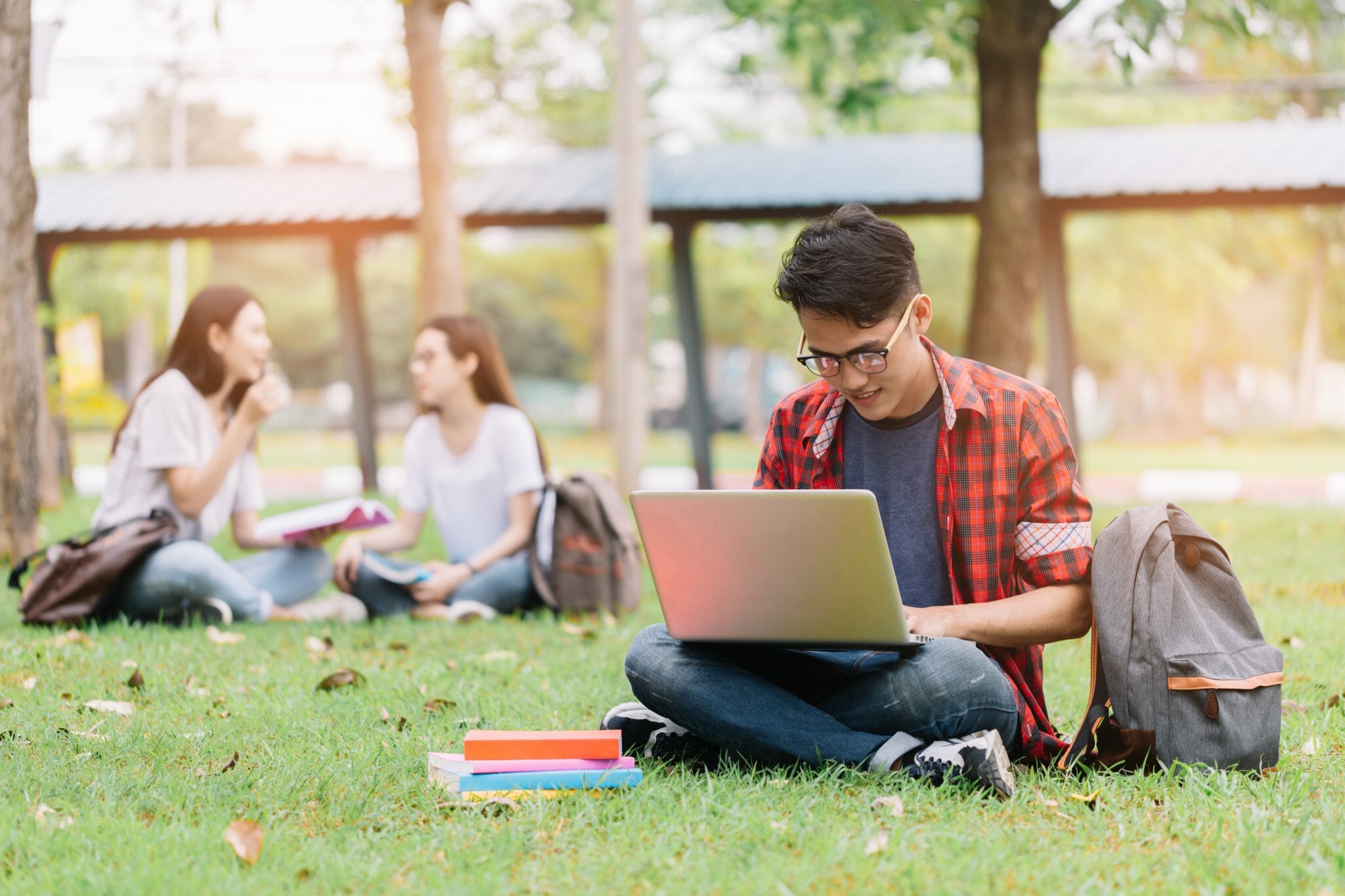 Young man sitting on grass working on a laptop