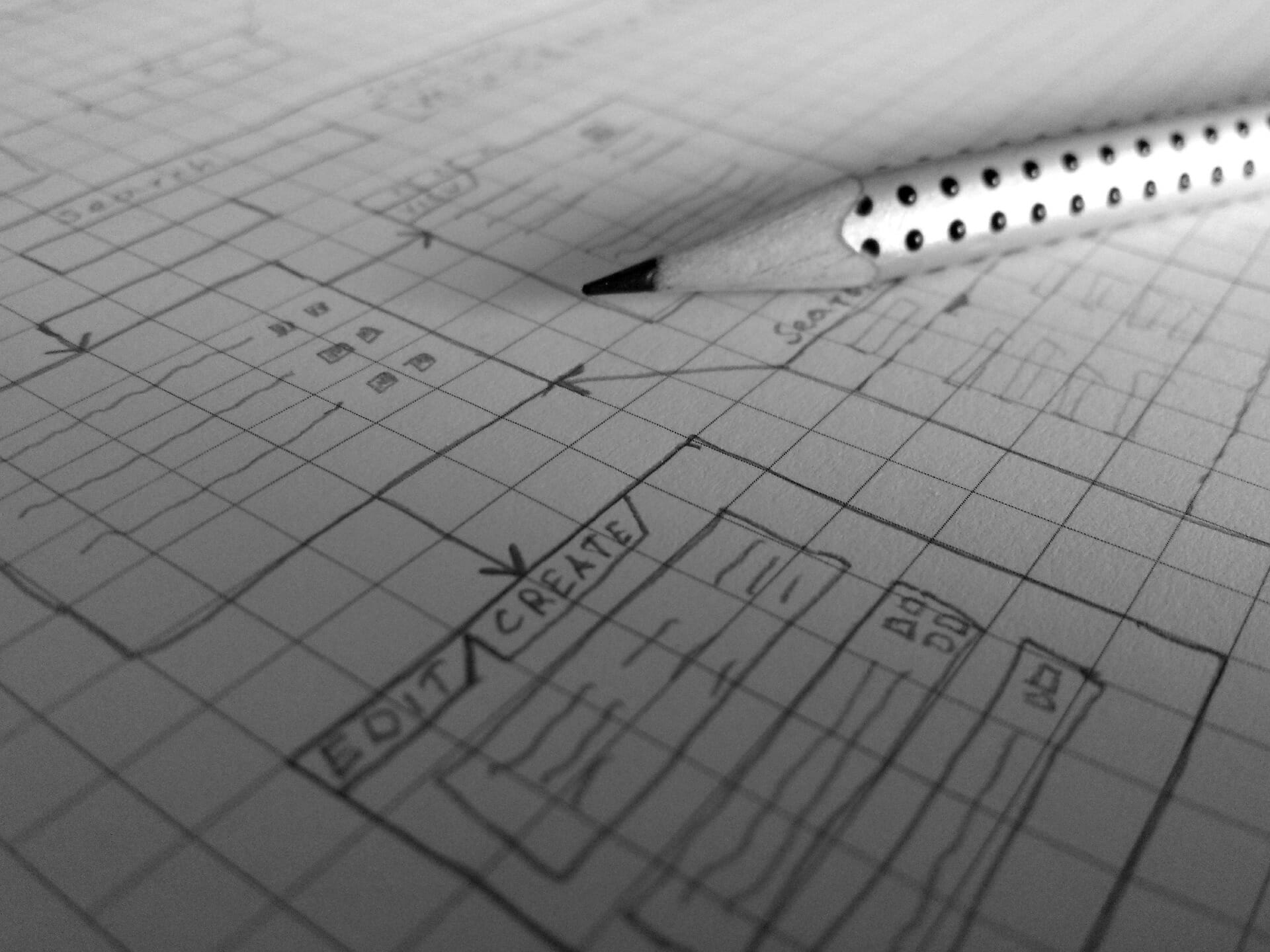 Pencil and graph paper with illustration of software plans