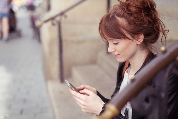 Woman sitting on some stairs looking at phone