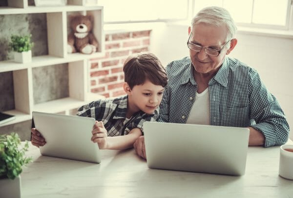 Child sitting with an old man at a laptop