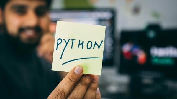 Person holding a sticky note that says Python